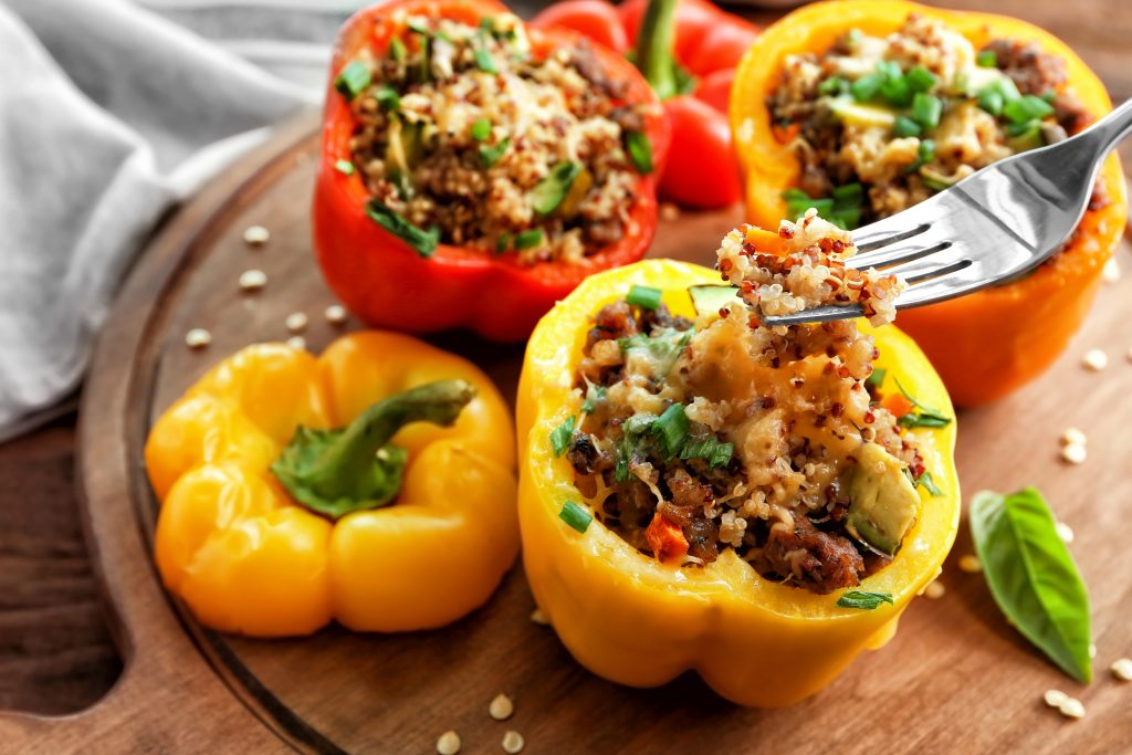 Eating of quinoa stuffed pepper on wooden board